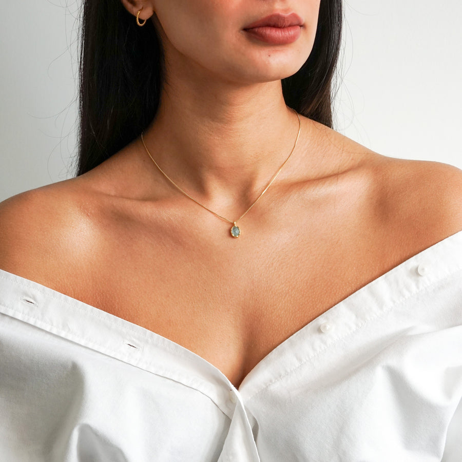 Aqua green oval aquamarine pendant with irregular faceting on an 18k gold vermeil box chain on model neck