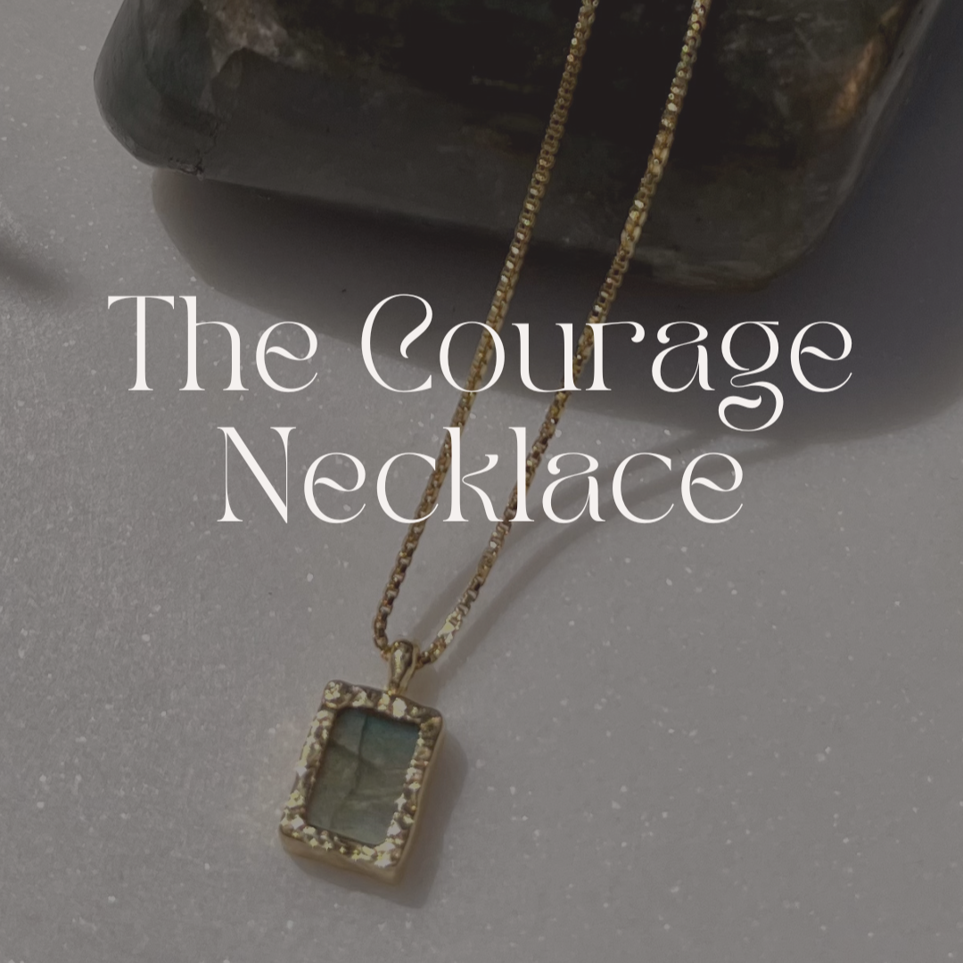 Necklace with a pendant on a gray surface, labeled 'The Courage Necklace'.