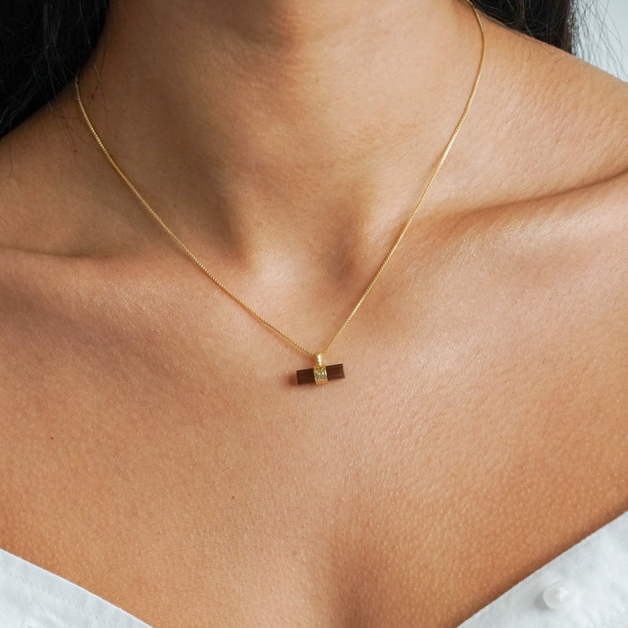 Dark brown smoky quartz pendant in a bar shape with a gold box chain on a models neck