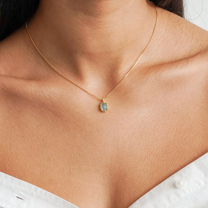 Aqua green oval aquamarine pendant with irregular faceting on an 18k gold vermeil box chain on model neck