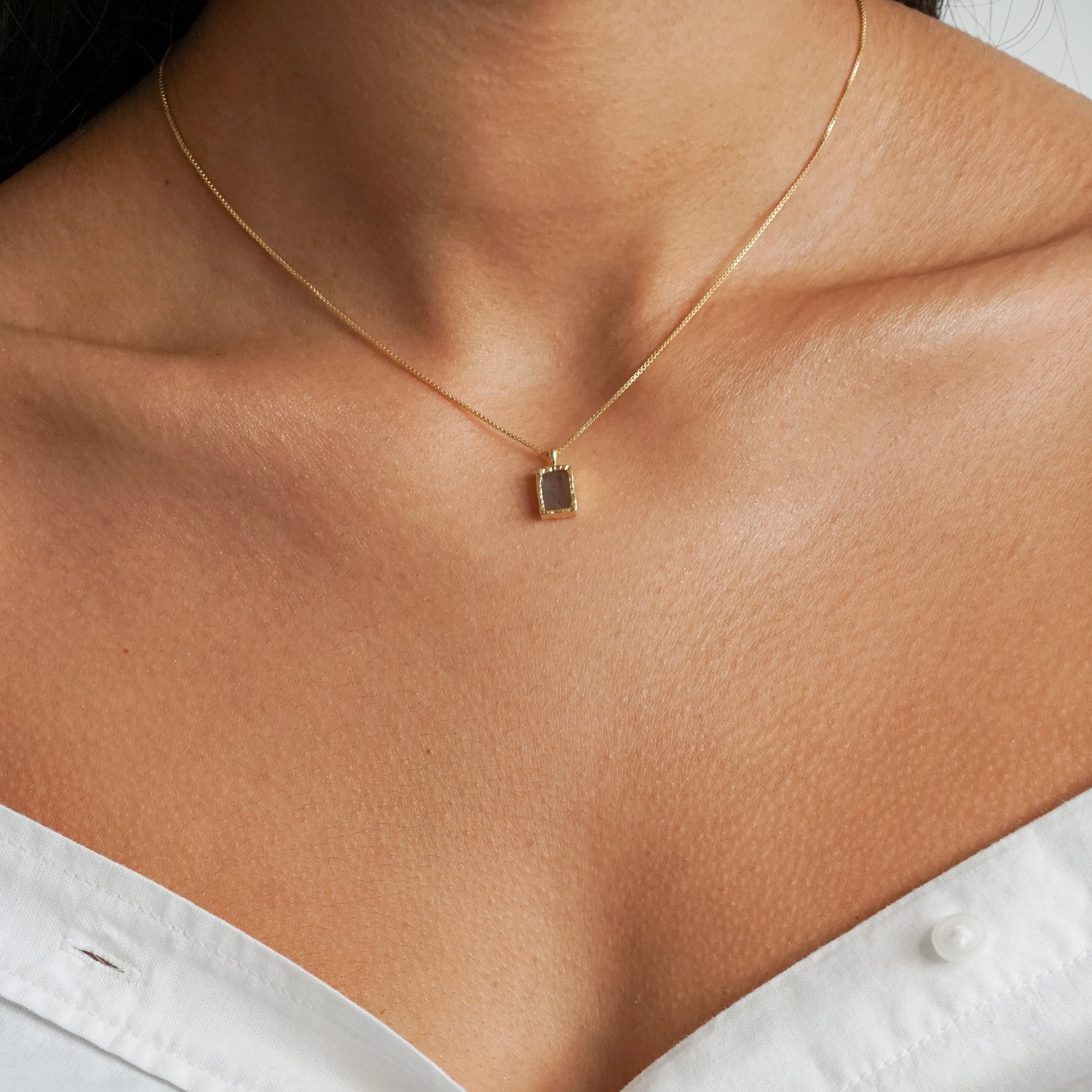 Rectangle flat labradorite pendant on an 18k gold box chain on a model neck close up