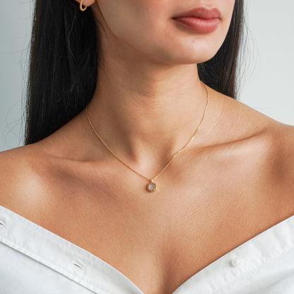 Flat round rainbow moonstone pendant on a 18k gold vermeil box chain on model neck
