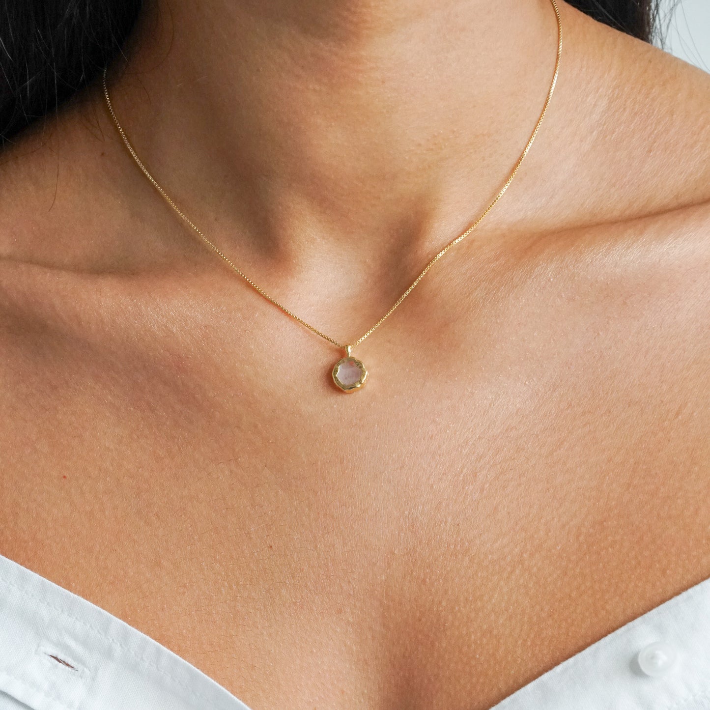 Flat round rainbow moonstone pendant on a 18k gold vermeil box chain on a model neck close up