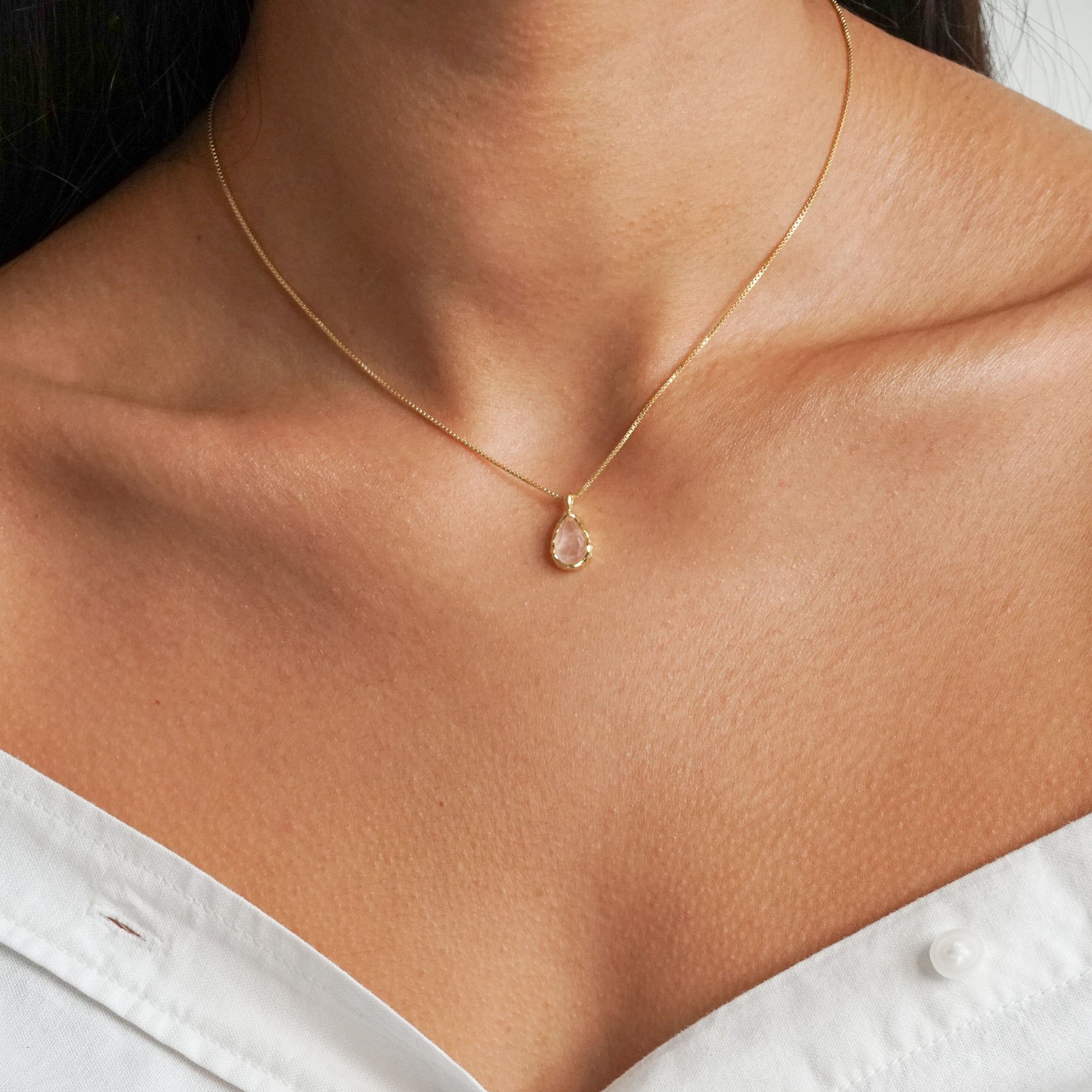 Teardrop shape pink rose quartz pendant with irregular faceting on a 18k gold vermeil box chain on a model neck close up